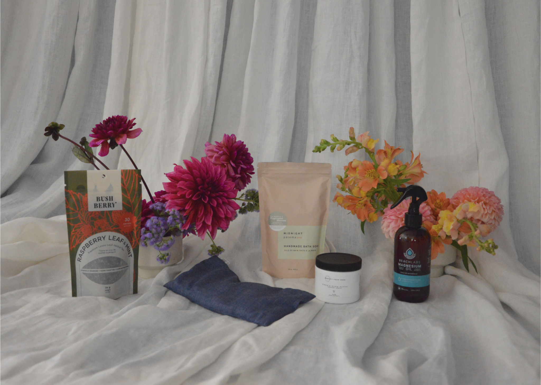 Assorted beauty and wellness products on a white fabric background with flowers.