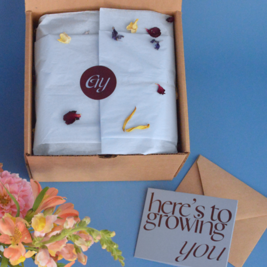 gift box with dried flowers, a card, and an envelope on a blue background