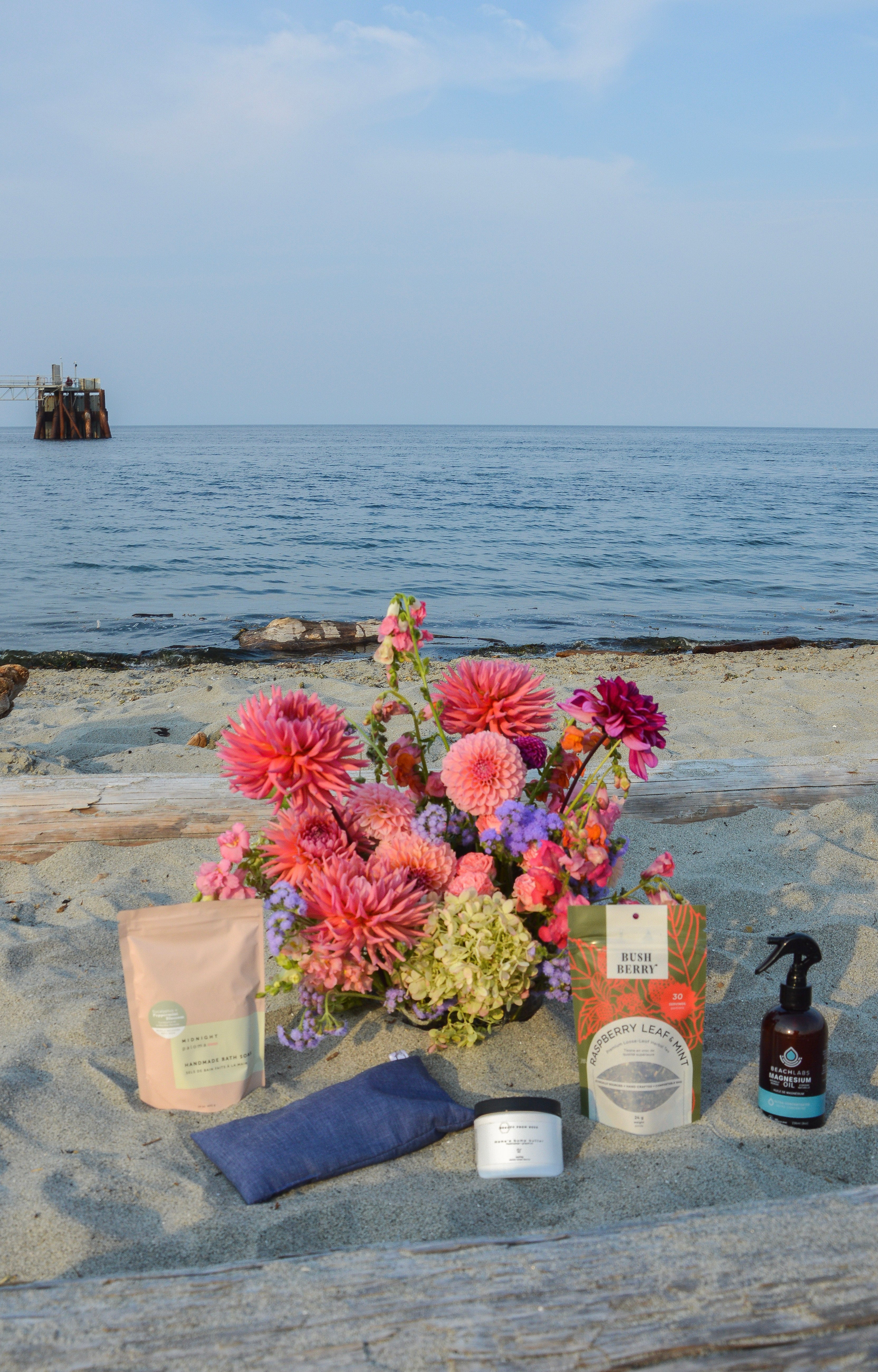 natural products and flowers on a beach with ocean and sky in the background gift box for mother to be